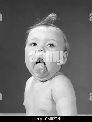 1960ER JAHRE BABY MIT CURL AUF KOPF & ZUNGE HERAUS Stockfoto