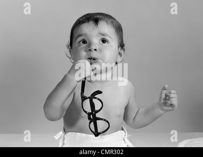 1960ER JAHREN BABY-WINDEL KAUEN AUF BRILLEN Stockfoto