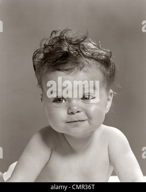 1950ER JAHRE PORTRAIT BABY MIT UNORDENTLICHEN LOCKEN & MIENE Stockfoto