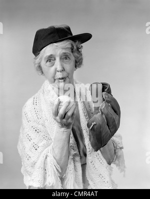 1950S 1960S OMA TRAGEN BASEBALL-MÜTZE & HANDSCHUH, PITCH-BALL BLICK IN DIE KAMERA Stockfoto