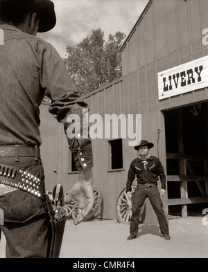 1950S 1960S TV-COWBOYS VOR MIETSTALL BEREIT, ZIEHEN PISTOLEN IM FEUERGEFECHT Stockfoto