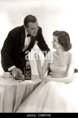 1950ER JAHRE FORMELLE KLEIDUNG PAAR MANN IM SMOKING FRAU TRAGEN KLEID MIT CHAMPAGNER GLAS Stockfoto