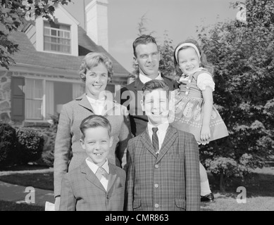 1960ER JAHREN FAMILIENPORTRÄT VATER MUTTER, ZWEI SÖHNE UND EINE TOCHTER VOR VORSTADTHAUS BLICK IN DIE KAMERA Stockfoto