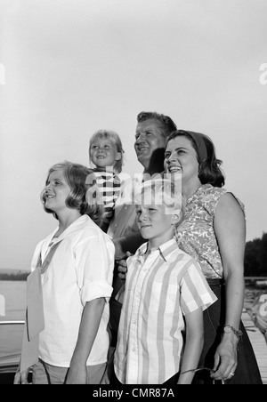 1960ER JAHREN LÄCHELND FAMILIE PORTRAIT VATER MUTTER 2 TÖCHTER SOHN ZUSAMMEN IM FREIEN STEHEN Stockfoto