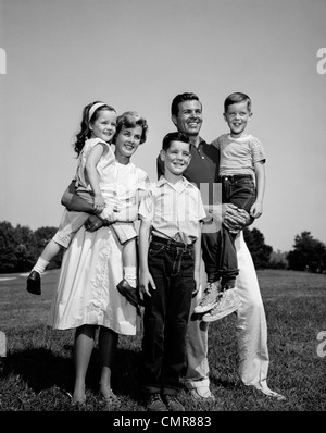 1960ER JAHREN FAMILIENPORTRÄT VATER MUTTER TOCHTER SOHN ZUSAMMEN IM FREIEN STEHEN Stockfoto