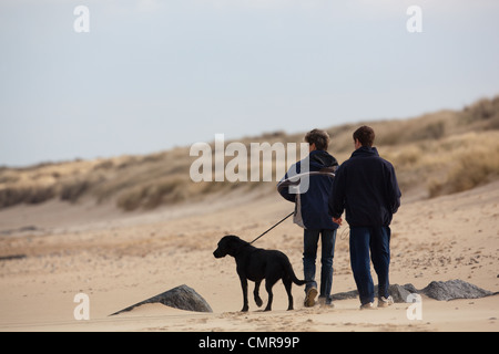 Hund-Wanderer. Verantwortlich Ehepaar und kontrollierte Haustier an der Leine. Norfolk-Strand. Stockfoto