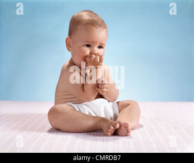 1960ER JAHREN ERNSTHAFTE BESORGNIS ERREGEND BABY SITZEN TRAGEN STOFFWINDEL Stockfoto