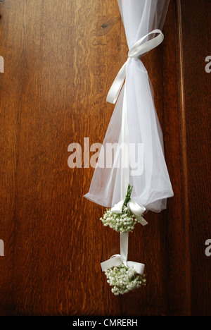 Hängenden weißen Hochzeitsblumen auf der vorderen Holztür einer Kirche Stockfoto