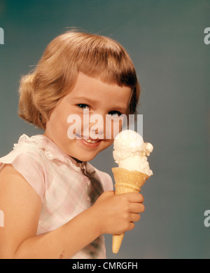 1950S 1960S LÄCHELNDE MÄDCHEN ESSEN EIS KEGEL DOUBLE SCOOP VANILLE Stockfoto