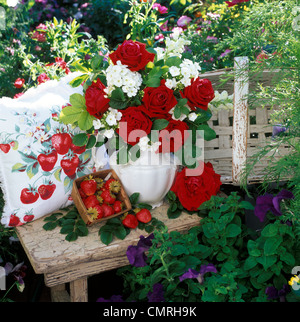 2000ER JAHRE BOUQUET VON ROTEN ROSEN UND WEIßEN BLUMEN IN VASE AUF GARTENBANK MIT ERDBEEREN Stockfoto