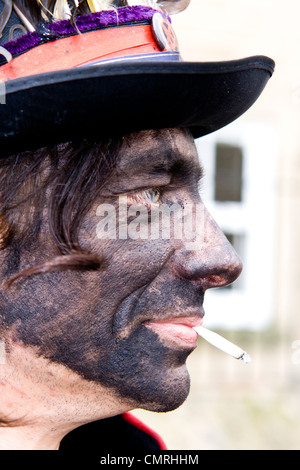 Porträt eines traditionellen schwarzen konfrontiert Morris Tänzer Rauchen einer Zigarette bei Bakewell Day des Tanzes Stockfoto