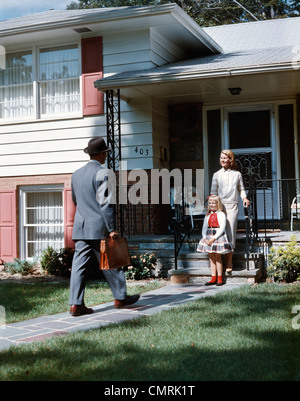 1950ER JAHRE MUTTER TOCHTER WARTEN SCHRITTE HAUS FÜR VATER AKTENTASCHE COMING HOME S FAMILIE MANN FRAU MÄDCHEN RETRO Stockfoto