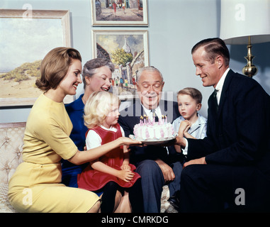 DREI-GENERATIONEN-FAMILIE MIT GEBURTSTAG KUCHEN GROßMUTTER GROßVATER VATER MUTTER SOHN TOCHTER INDOOR Stockfoto