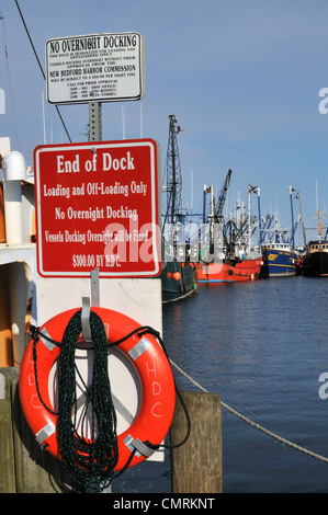 Warnschilder am Ende des Kai mit Blick auf die Fischereiflotte im Hafen von New Bedford, Massachusetts Stockfoto