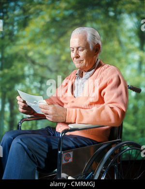 1970 1970S RETRO-ZUSAMMENGESETZTES BILD LÄCHELND SENIOR ÄLTEREN MANN SITZT IM ROLLSTUHL LESEN BUCHSTABEN IM WALD NATUR IM FREIEN Stockfoto