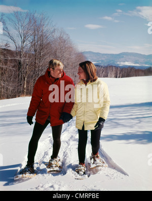 1970 1970S RETRO MANN FRAU ZU FUß SCHNEE SCHNEESCHUHE Stockfoto