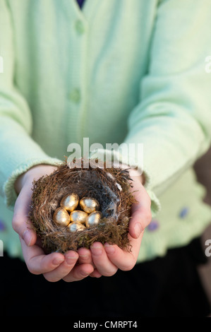 Mädchen mit goldenen Eiern in einem Vogelnest Stockfoto