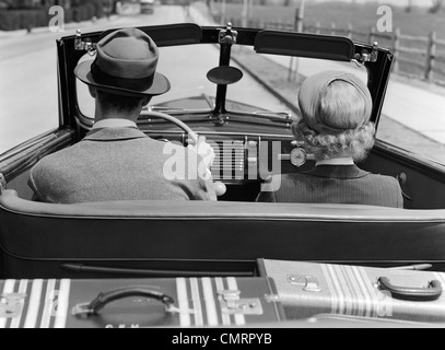 1930S 1940S REAR VIEW PAAR FAHRERSITZ ZUSAMMEN IM CABRIO GEPÄCK AUF DER RÜCKSEITE Stockfoto