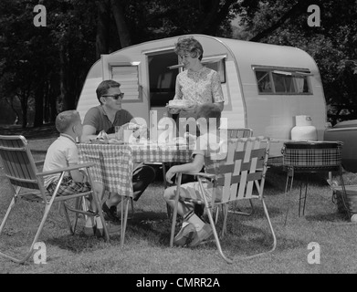 1960ER JAHREN FAMILIEN-CAMPINGPLATZ ESSEN MAHLZEIT NEBEN RV CAMPER Stockfoto