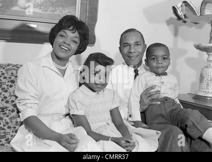 1960ER JAHREN GLÜCKLICH LÄCHELNDE AFRO-AMERIKANISCHE FAMILIE AUF COUCH Stockfoto