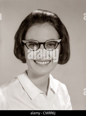 1960ER JAHREN LÄCHELND PORTRAIT FRAU TRÄGT HORNBRILLE BLICK IN DIE KAMERA Stockfoto