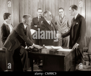 1930ER JAHRE GRUPPE GESCHÄFTSMÄNNER UND FRAU IM BÜRO CHEF SCHÜTTELN HÄNDE MIT NEUER MITARBEITER Stockfoto