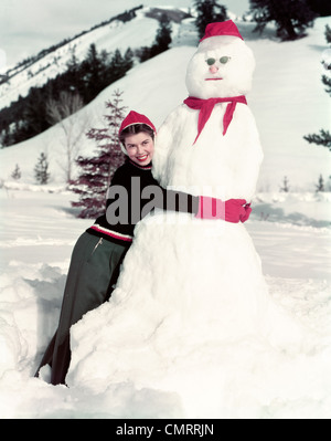 1940S 1950S LÄCHELNDE FRAU UMARMT SCHNEEMANN Stockfoto