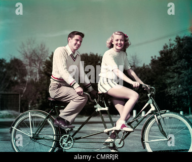 1950ER JAHREN LÄCHELND PAAR TANDEM FAHRRAD FÜR ZWEI GEBAUT Stockfoto