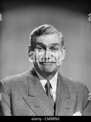 REIFE MITTE DER 1950ER JAHRE ALTER MANN LÄCHELND BUSINESS ANZUG KRAWATTE AMÜSIERT LUSTIGE SMILEY AUSDRUCK Stockfoto