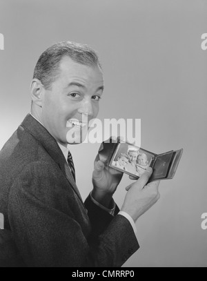 1950S 1960S MANN LÄCHELND BRIEFTASCHE MIT FOTO DER FAMILIE BLICK IN DIE KAMERA HALTEN Stockfoto
