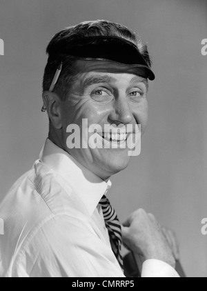 1950ER JAHRE PORTRAIT MANN BUCHHALTER TRAGEN AUGE SCHATTEN VISIER MIT BLEISTIFT HINTER OHR BLICK IN DIE KAMERA LÄCHELN Stockfoto