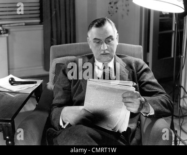 1930S 1940S ÄLTEREN GESCHÄFTSMANN SITZT IM SESSEL LESEN ZEITUNG Stockfoto