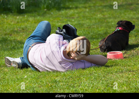Frau und ihr Hund Faulenzen auf der Wiese an einem Frühlingstag - Christus Kirche College Wiesen während der Times Literary Festival 2012 Stockfoto