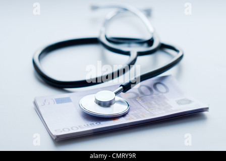 Stethoskop mit Haufen Geld auf grauem Hintergrund Stockfoto