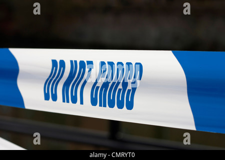 Polizei-Band für Tatort mit "Nicht kreuzen" in blauer Schrift auf weißem Stoff unscharf generische Detail im Hintergrund. Stockfoto