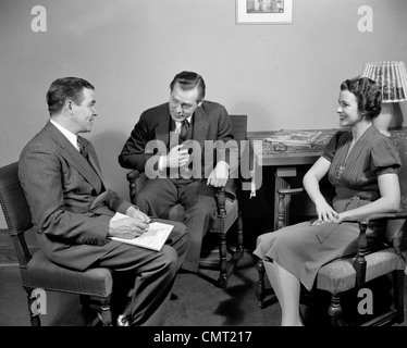 1930S 1940S VERKÄUFER IM GESPRÄCH MIT PAAR MANN UND FRAU IM WOHNZIMMER VERKAUFSPRÄSENTATION Stockfoto