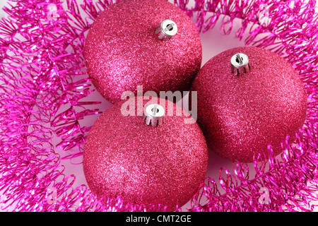 Draufsicht der drei rote Christbaumkugeln umgeben von lila Lametta isoliert auf weiss. Stockfoto