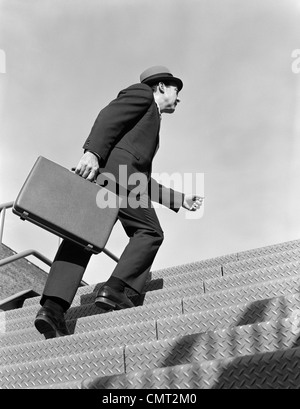 1960ER JAHRE VERKÄUFER GESCHÄFTSMANN AKTENTASCHE IN DER HAND TREPPEN STEIL HARTE STAHL LAUFFLÄCHE SYMBOLISCHE IM FREIEN Stockfoto