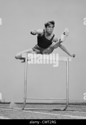 1960S 1970S RUNNING MAN EINEN SPRUNG ÜBER DIE HÜRDE Stockfoto