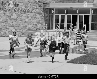1960ER JAHREN JUNGEN UND MÄDCHEN SCHÜLER AUS DER SCHULE LAUFEN Stockfoto