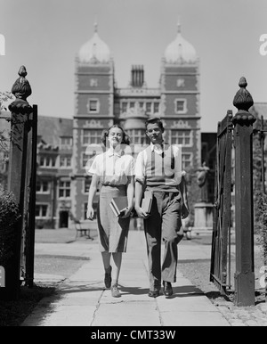 1940ER JAHRE COLLEGE IM ALTER STUDENT PAAR ZU FUß DURCH CAMPUS GATES UNIVERSITÄT VON PENNSYLVANIA Stockfoto