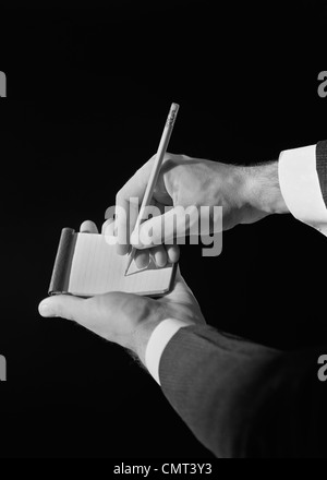 1930ER JAHRE MANN DIE HÄNDE AUF NOTIZBLOCK MIT BLEISTIFT SCHREIBEN Stockfoto