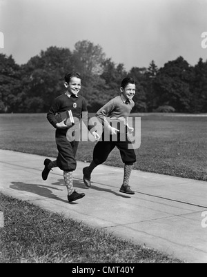 1930S 1940S SCHULE ZWEI LÄCHELNDE JUNGEN LAUFEN TRAGEN BÜCHER Stockfoto