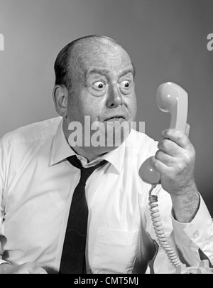 1960S 1970S BÖSE GLATZE MANN GLUBSCHÄUGIGEN BLICK IN TELEFONHÖRER Stockfoto