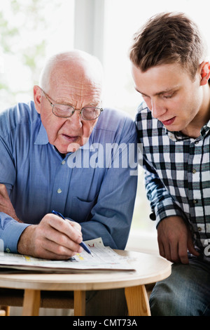 Ältere Mann mit Enkel Kreuzworträtsel zu lösen Stockfoto