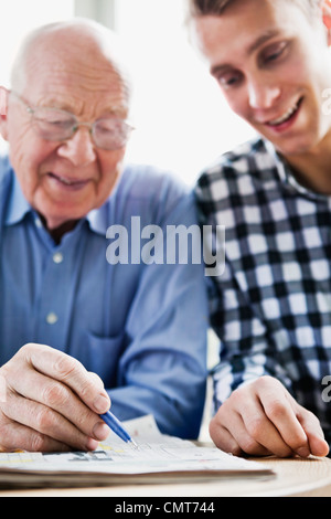 Guy und ältere Mann lösen Kreuzworträtsel Stockfoto