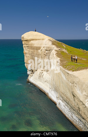 Touristen auf Klippe am Tunnel Beach, Dunedin, Südinsel, Neuseeland Stockfoto