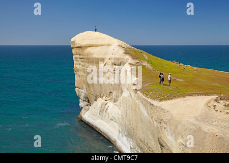 Touristen auf Klippe am Tunnel Beach, Dunedin, Südinsel, Neuseeland Stockfoto