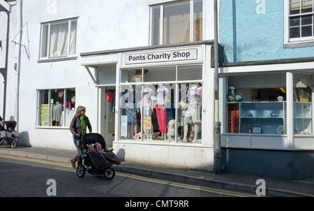 Eine Frau mit einem Kinderwagen geht die Hose Charity-Shop in Falmouth, England Stockfoto