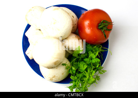 Eine Reihe von Pilzen, Tomaten und Unterredung werden auf auf eine blaue Platte platziert. Geringe Schärfentiefe. Stockfoto
